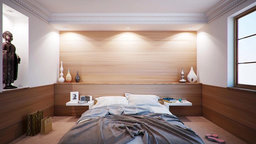 Slaapkamer met een laag bed en een houten wand met ingebouwde verlichting