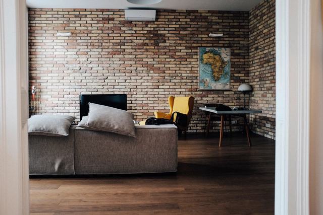 Living met een grijze zetel en een bakstenen muur