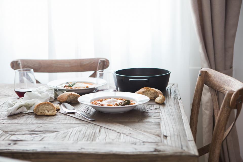 Houten eettafel met borden, brood en houten stoelen bij het raam